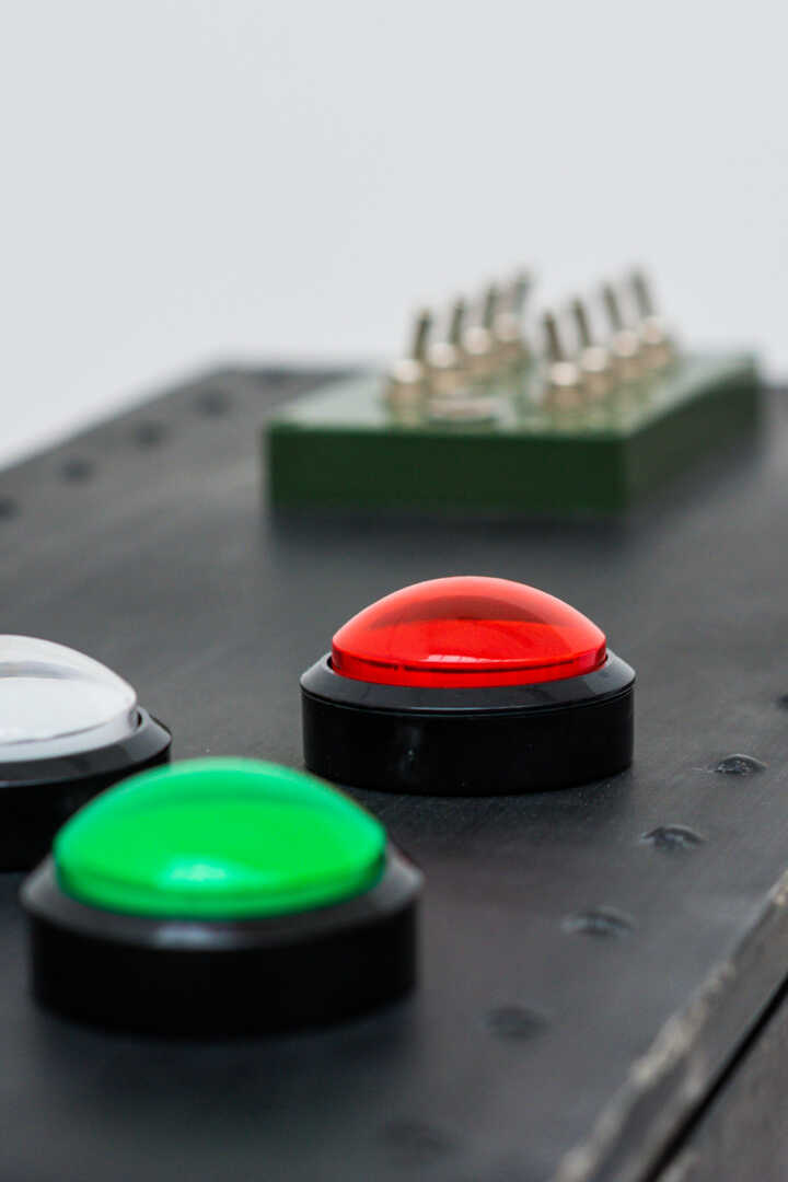 Close-up of a control panel with colored buttons: yellow, white, red, green, and a green switch.