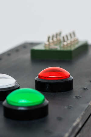 Close-up of a control panel with colored buttons: yellow, white, red, green, and a green switch.